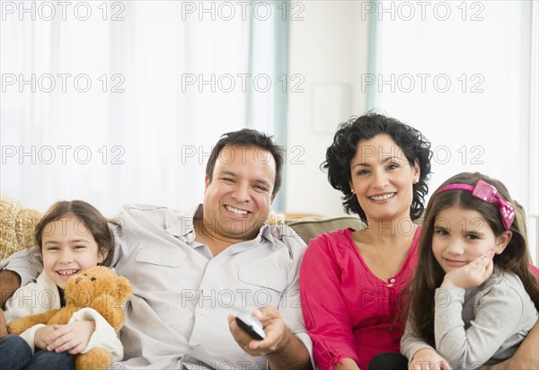 Family watching television together on sofa