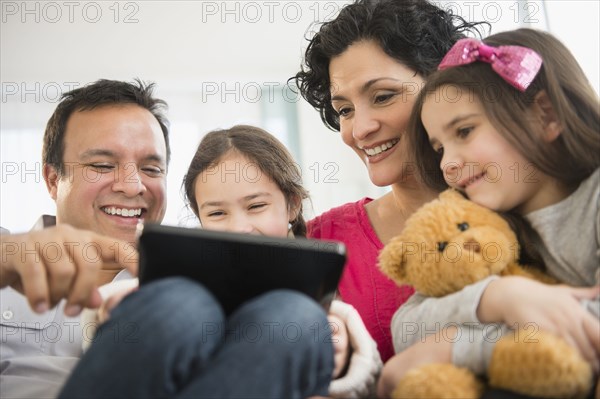 Family using digital tablet together on sofa