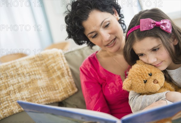 Mother and daughter reading together on sofa