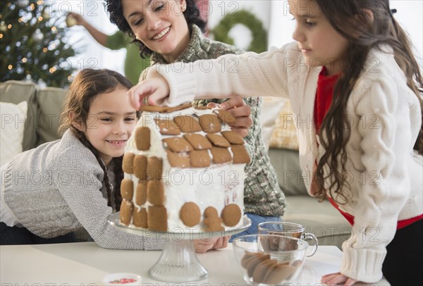 Mother and daughters making gingerbread house