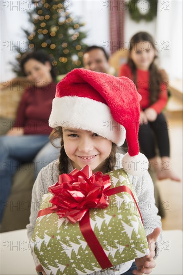 Girl in Santa hat holding Christmas present