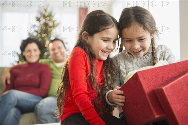 Smiling girls opening Christmas present