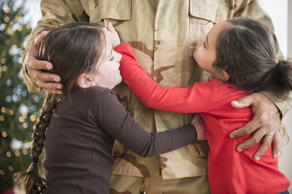 Daughters hugging soldier father