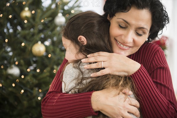 Mother and daughter hugging by Christmas tree