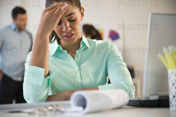 Businesswoman rubbing her forehead at desk