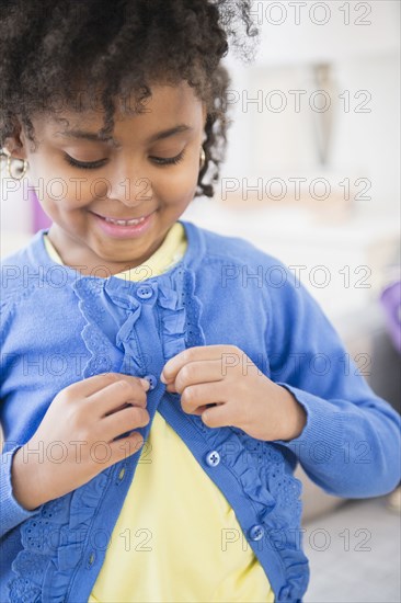 African American girl buttoning her cardigan