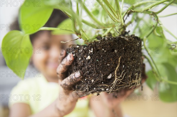 African American girl holding de-potted plant