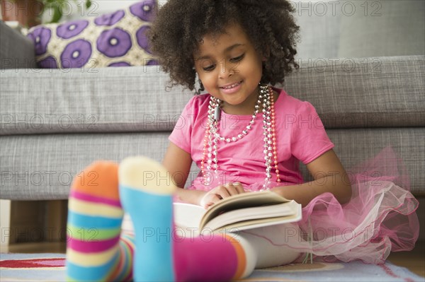 African American girl reading in living room