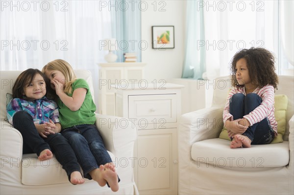 Girls whispering away from friend in living room