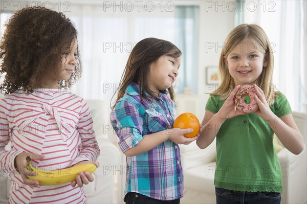 Girls eating fruit and donut in living room