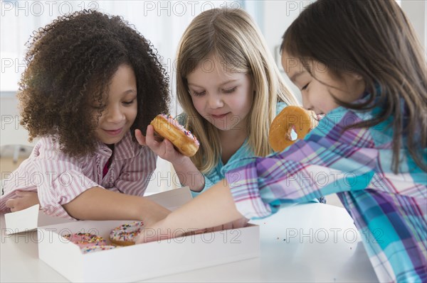 Girls eating donuts together in kitchen