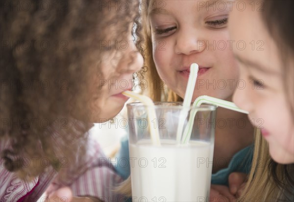 Girls sharing glass of milk