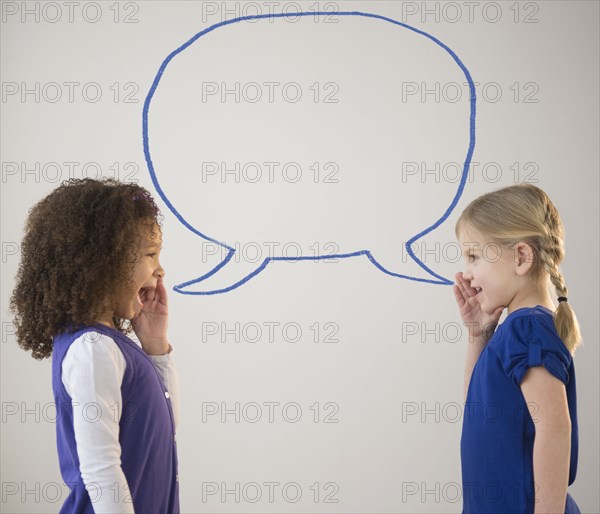 Girls whispering with empty speech bubble