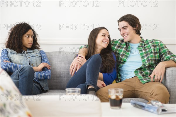 Couple ignoring friend on sofa