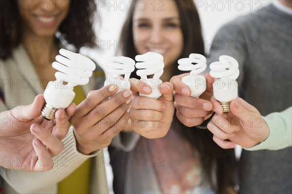 Friends holding fluorescent light bulbs