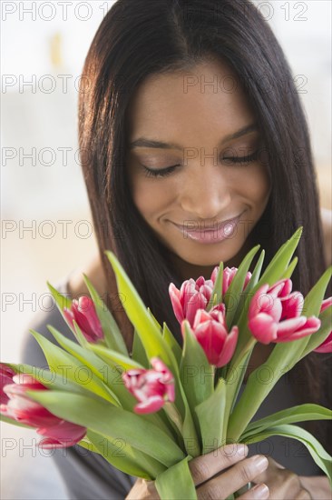 Mixed race woman smelling flowers