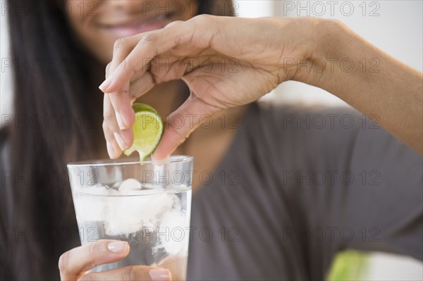 Mixed race woman squeezing lime into drink