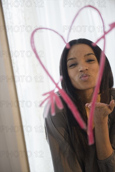 Mixed race woman blowing kiss in mirror