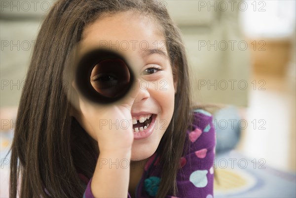 Hispanic girl playing with cardboard tube