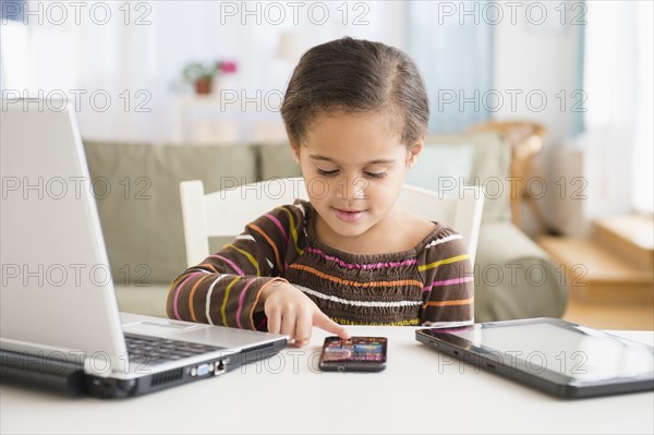 Hispanic girl using cell phone at desk