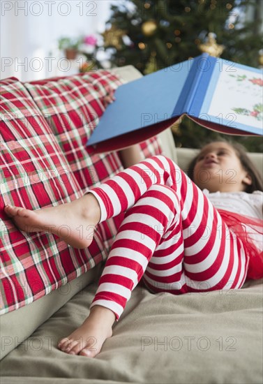 Hispanic girl reading on sofa