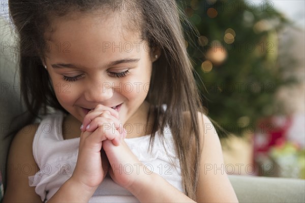 Hispanic girl praying on sofa