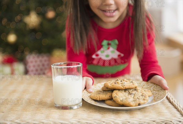 Hispanic girl setting out milk and cookies for Santa