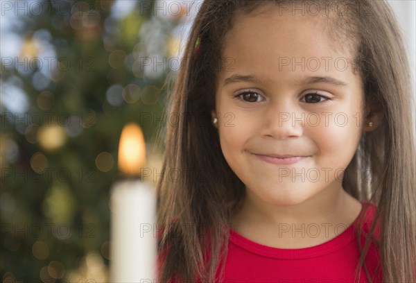 Hispanic girl smiling by lit candle