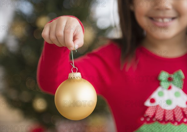 Hispanic girl holding Christmas ornament