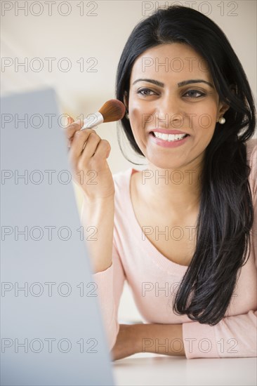 Indian woman applying makeup in mirror