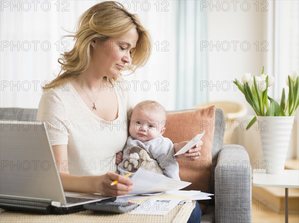 Caucasian mother with baby paying bills