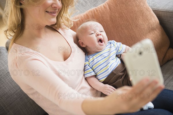 Caucasian mother taking picture of herself and baby