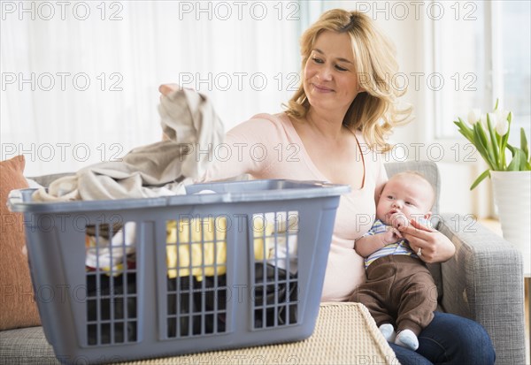 Caucasian mother with baby sorting laundry