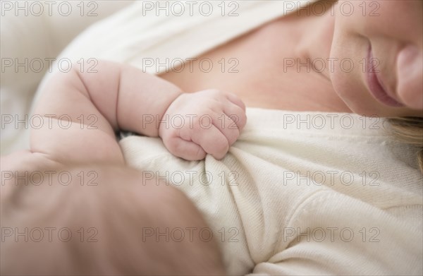 Caucasian baby gripping mother's sweater