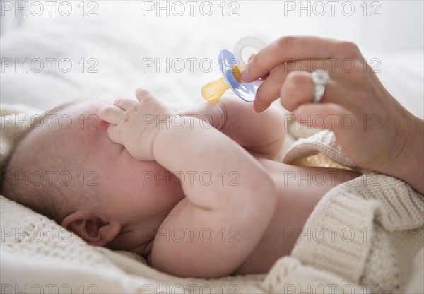 Caucasian mother giving baby pacifier