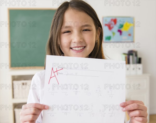 Mixed race girl holding paper with A+ grade