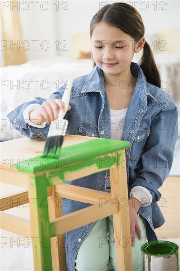 Mixed race girl painting stool