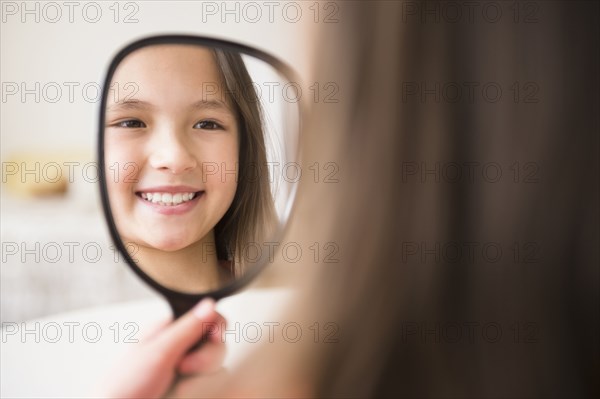 Mixed race girl admiring herself in mirror