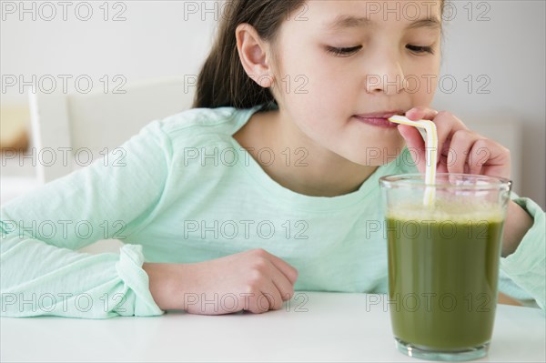 Mixed race girl drinking green smoothie