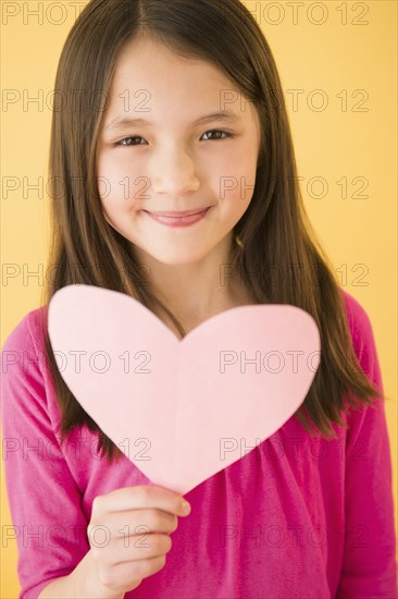 Mixed race girl holding heart