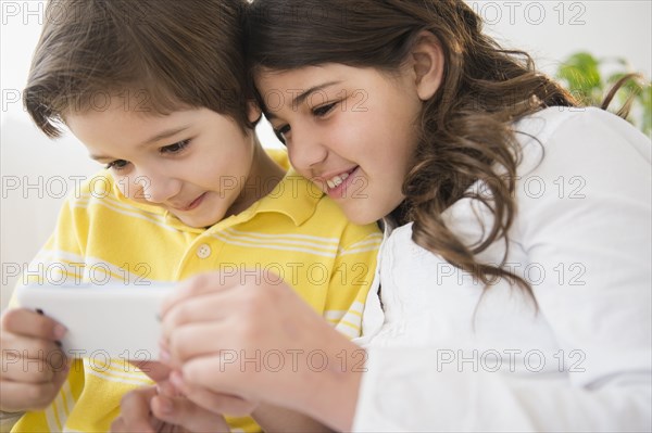 Hispanic children using cell phone together