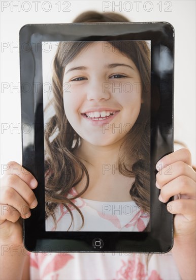 Hispanic girl holding tablet with picture of her face