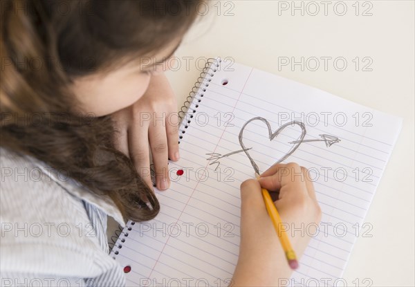 Hispanic girl doodling heart and arrow