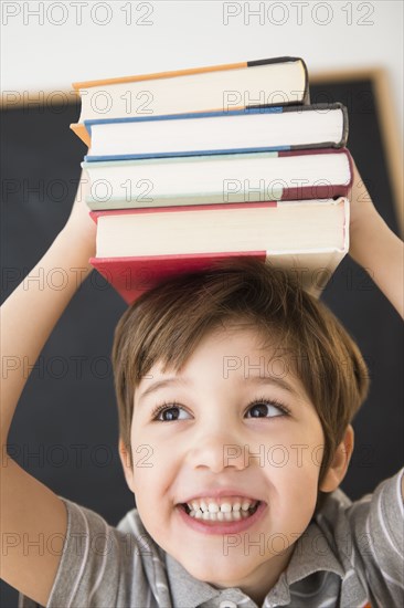 Hispanic boy balancing books on head