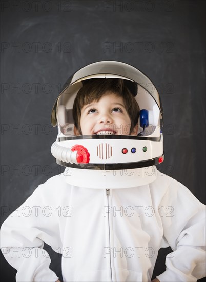 Hispanic boy wearing space helmet in classroom