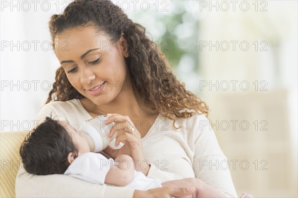 Hispanic mother bottle feeding infant son