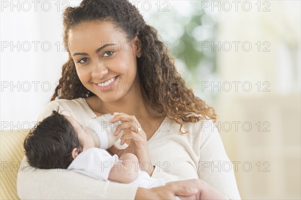 Hispanic mother bottle feeding infant son