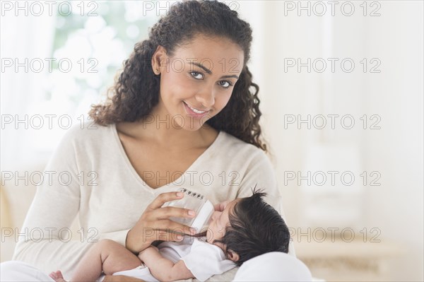 Hispanic mother bottle feeding infant son