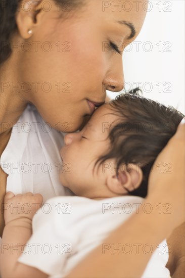 Hispanic mother kissing infant son