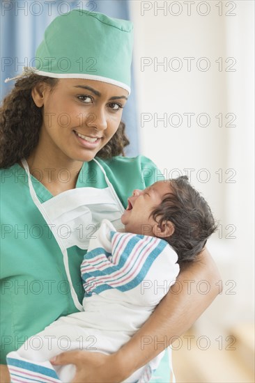 Hispanic doctor holding newborn in hospital